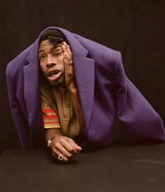 a man is covering his face with a purple blanket