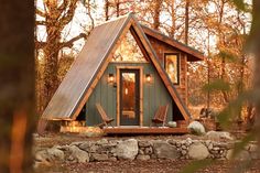 a small cabin in the woods surrounded by rocks and trees with fall foliage around it