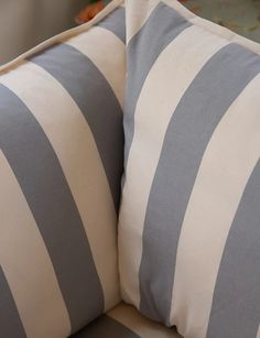 two gray and white striped pillows sitting on top of a couch next to each other