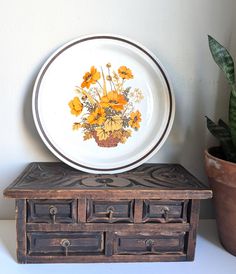 a plate sitting on top of an old wooden box next to a potted plant