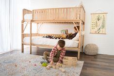 two children are playing with blocks on the floor in front of a bunk bed and another child is reading