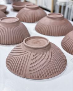 many brown vases sitting on top of a white table covered in chocolate frosting