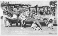 an old black and white photo of children posing for a picture with a large alligator