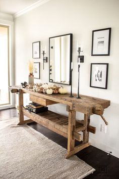 a wooden table sitting in the middle of a living room with pictures on the wall