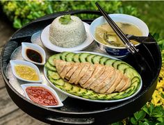 a plate with rice, cucumber slices and sauces on it sitting on a table