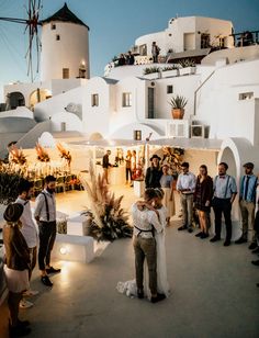 a group of people standing around each other in front of white buildings with windmills