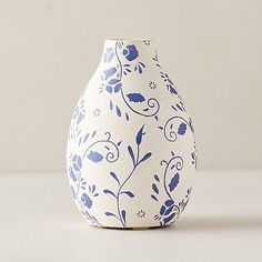 a blue and white vase sitting on top of a table next to a wall behind it