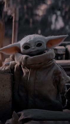 the child yoda from star wars is sitting on a table and looking at something