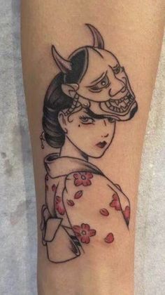 a tattoo on the leg of a woman with a geisha mask and flowers in her hair