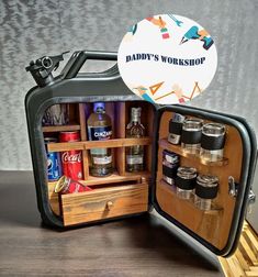 an open suitcase with various items in it on a wooden table next to a sign that says daddy's workshop