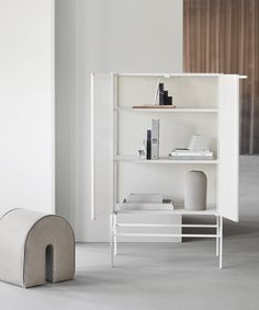 a white book shelf with books on it and a dog house in the corner next to it