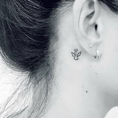 a woman's ear with a small tattoo on it