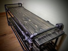 an old metal table with pipes on it and wood flooring next to the wall