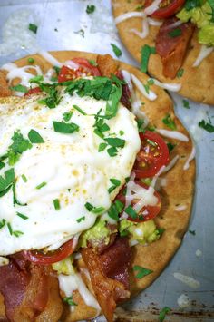 two pizzas with bacon, lettuce and an egg on top are shown