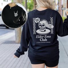 "*This shirt has a design on the FRONT & BACK* Step back in time and relive the golden era of emo music with our Elder Emo Music Sweatshirt. This comfy sweatshirt is the perfect choice for those who still carry the spirit of emo in their hearts. Featuring a captivating design of a beautifully detailed skull and a defiant \"rock on\" hand gesture, this shirt is a must-have for any elder emo enthusiast. Whether you're searching for an emo gift or wanting to express your undying love for the emo subculture, this scene shirt is the ultimate statement piece. Wear it proudly to the When We Were Young Festival or any other music event, and let the world know that your emo spirit is alive and thriving. It's not just a phase; it's a way of life. Embrace the everlasting emo culture with our Elder Em Emo Sweatshirt With Letter Print And Crew Neck, Emo Crew Neck Sweatshirt With Letter Print, Emo Style Crew Neck Sweatshirt With Letter Print, School Crew Neck Sweatshirt With Graphic Print, Emo Style Cotton Crew Neck Sweatshirt, Casual Crew Neck Sweatshirt For Concert, Punk Sweatshirt With Letter Print And Crew Neck, School Band Merch Tops With Graphic Print, Band Merch Graphic Print Top For School