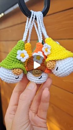 someone is holding two small crocheted ornaments in their hands and they are wearing hats with flowers on them