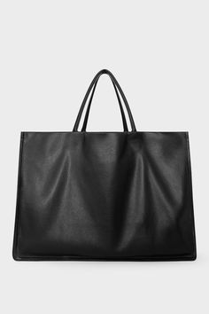 An extra-large black tote bag with a square body. It has an open top with two magnetic closures. The bag has 2 handles to be carried handheld or as a shoulder bag. Structured Soft Leather Shopping Bag, Minimalist Smooth Grain Shoulder Bag For Shopping, Sleek Textured Leather Tote Bag, Chic Bags With Smooth Grain Finish, Minimalist Structured Bag With Top Carry Handle, Minimalist Structured Bags With Top Carry Handle, Minimalist Rectangular Shoulder Bag With Rolled Handles, Minimalist Tote Bag With Smooth Grain, Minimalist Smooth Grain Tote Shoulder Bag