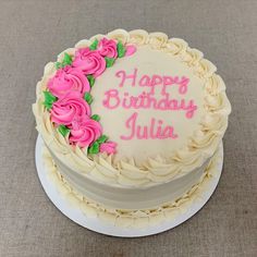 a birthday cake with white frosting and pink flowers on top that says happy birthday julia