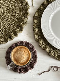 a cup of coffee sitting on top of a saucer next to a crocheted doily