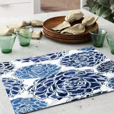 a blue and white place mat on top of a table next to green glass cups