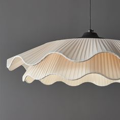 a light fixture hanging from the ceiling with pleated fabric on it's sides