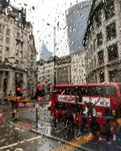 rain is falling on the window of a red double decker bus