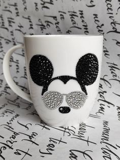 a coffee cup with mickey mouse's head and glasses on it, surrounded by handwritten letters