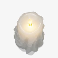 a white candle with a small light in it's center on a white background