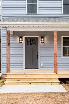 a blue house with a gray front door and steps leading up to the front door