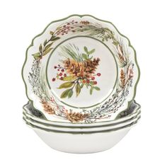 three white dishes with green trim and pine cones on the rims, each decorated with holly