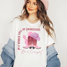 "Looking for a vintage western cowgirl t-shirt that will make you say \"In a world full of princesses, be a cowgirl!\" Look no further than this oversized comfort colors tee. Perfect as a western shirt, t-shirt dress, or cowgirl t-shirt, this tee features a bold western graphic that is sure to turn heads. With its vintage style and classic cowgirl shirt design, this tee is a must-have for any cowgirl looking to add some Shania flair to their wardrobe. So what are you waiting for? Saddle up and grab your own cowgirl tee today! See my shop for other options.  Click link below. https://www.etsy.com/shop/StaySmartDesign?ref=seller-platform-mcnav *Comfort color garment dyed shirts are super popular right now and these cotton washed tees are the nicest, softest shirts to wear. The colors are tru Cowgirl T Shirt, Cowgirl Tshirt, Classic Cowgirl, Dress Western, Cowgirl Look, Oversized T Shirt Dress, Western Vintage, Look Retro, Cowgirl Shirts