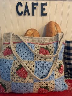 a crocheted bag sitting on top of a table next to two doughnuts