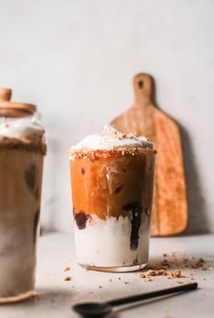 two iced drinks sitting on top of a table next to a knife and cutting board