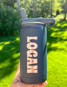 a person holding up a blue insulated water bottle with the words yoga on it