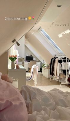 an attic bedroom with clothes hanging from the ceiling, and a bed in the foreground