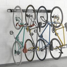 three bicycles are mounted to the wall with wheels on it's hooks and hangers