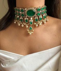 Inspired by the opulent designs of Sabyasachi, this emerald green Victorian choker set is the epitome of elegance and timeless beauty. The choker, meticulously crafted, features a central emerald stone surrounded by intricate gold filigree work that echoes the grandeur of the Victorian era. Each detail is a testament to the exquisite craftsmanship, with tiny pearls and delicate gold beads enhancing the necklace's regal appeal. Complementing the choker are a pair of matching earrings that mirror Indian Choker Necklace Set, Ambani Wedding, Victorian Choker, Unique Wedding Jewelry, Indian Choker, Indian Choker Necklace, Neck Pieces Jewelry, Sabyasachi Jewellery, Pearl Jewelry Design