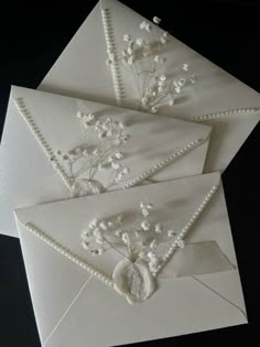 three envelopes with pearls and flowers on them