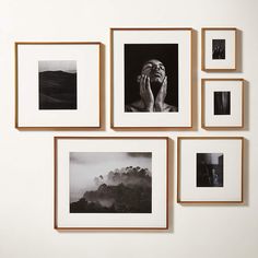 four framed photographs hang on the wall above them are black and white photos, with one woman's face in her hands