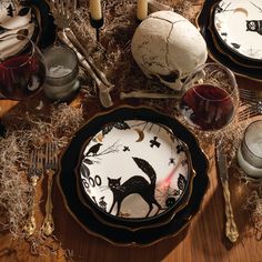 a halloween table setting with skulls, candles and plates