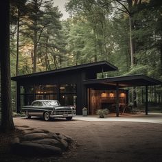 a black car is parked in front of a house surrounded by tall trees and evergreens