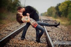 a man and woman kissing on train tracks