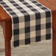 a black and white checkered table runner sitting on top of a wooden table next to a chair