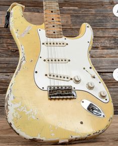 an old yellow guitar sitting on top of a wooden table