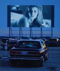 a car parked in front of a large screen with a woman's face on it