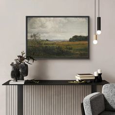 a painting hanging on the wall next to a chair and vase with flowers in it