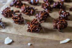 pieces of chocolate are sitting on top of brown paper and scattered with white flakes