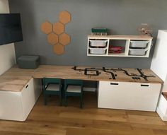 a room with a desk, shelves and two bins on the wall next to each other