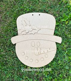 a wooden snowman on the grass with its name cut out and placed next to it