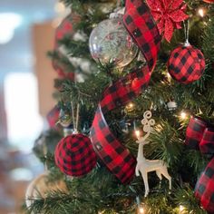 a christmas tree decorated with red and black plaid ribbon, ornament ornaments and a deer